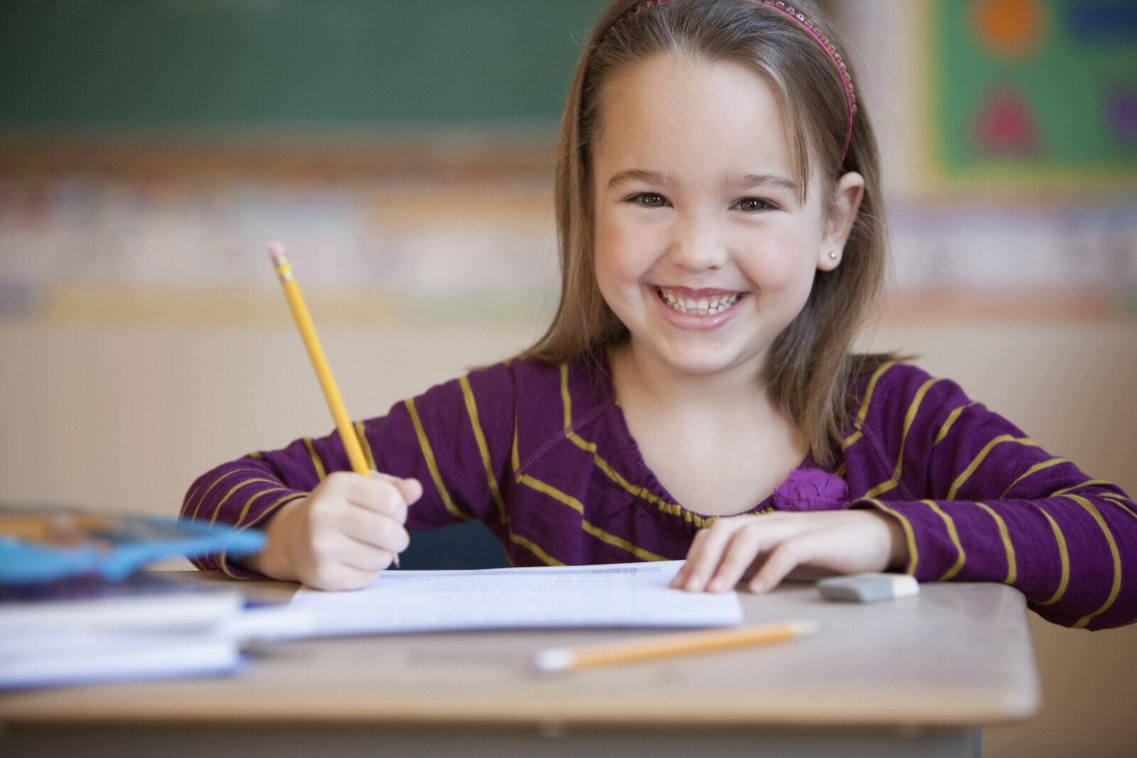 A smiling elementary school student writing at her desk