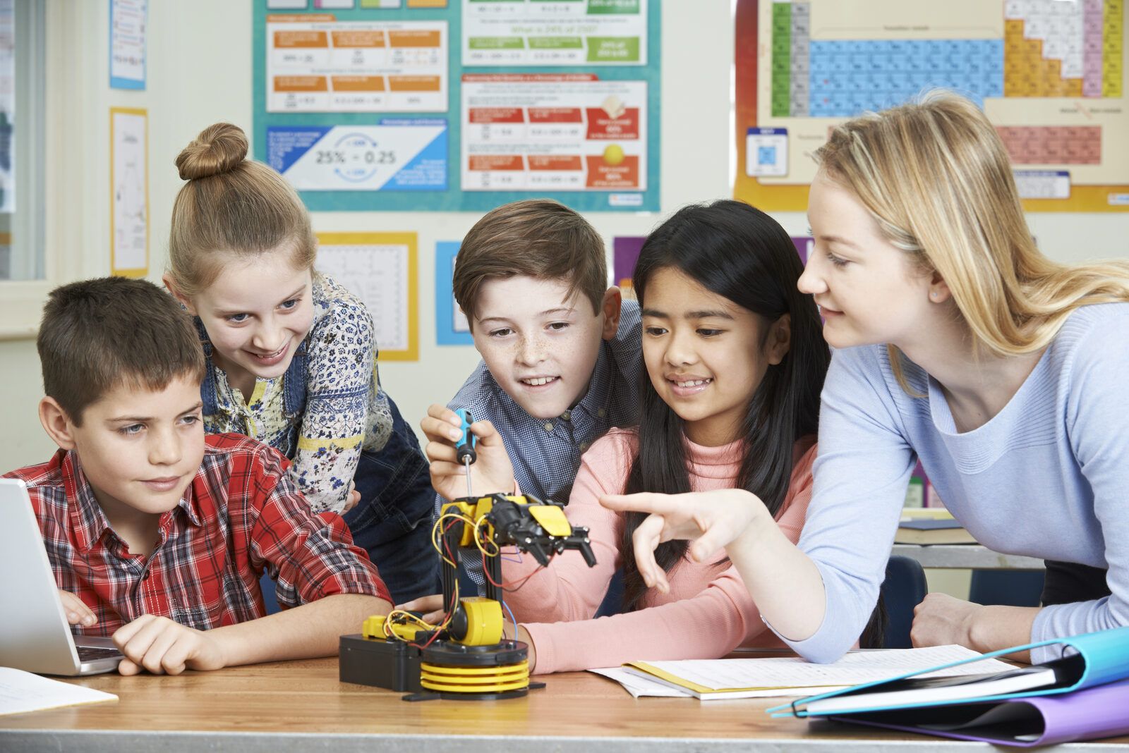 A teacher works with elementary students on a hands-on classroom project