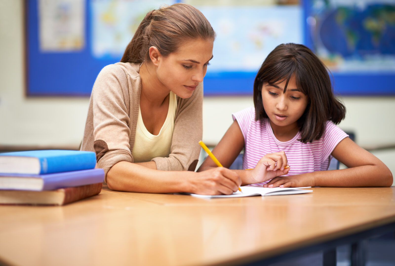 A teacher helping a student with schoolwork at a desk